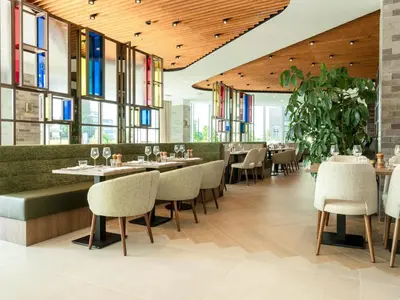 a restaurant with tables and chairs and windows at Hilton Garden Inn Brussels Airport in Diegem