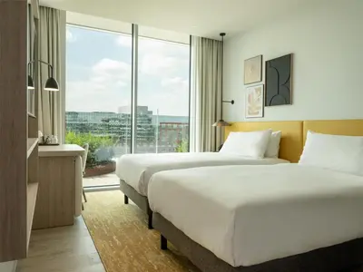 two beds in a hotel room with a large window at Hilton Garden Inn Brussels Airport in Diegem
