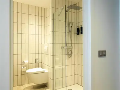 a bathroom with a toilet and a glass shower at Hilton Garden Inn Brussels Airport in Diegem