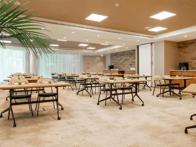 a conference room with tables and chairs and a palm tree at Hilton Garden Inn Brussels Airport in Diegem