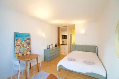 a bedroom with a bed and a table and a kitchen at Beautiful and bright apt AvLouise in Brussels