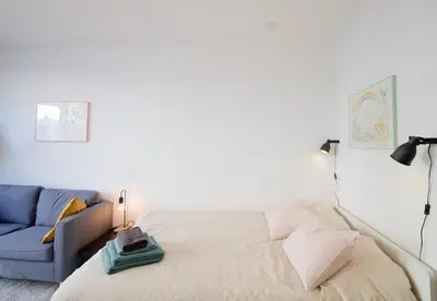 a bedroom with a bed and a blue couch at Brand new & cosy - Louise & Stéphanie area in Brussels