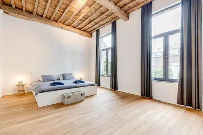 a white bedroom with a bed and large windows at Beautiful spacious Loft in the Heart of Antwerp in Antwerp