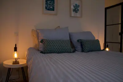 a bed with blue sheets and a lamp on a table at Charming Apartment with Cathedral View in Antwerp on the 2th floor in Antwerp