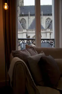 a bed in front of a window with a view of a building at Charming Apartment with Cathedral View in Antwerp on the 2th floor in Antwerp