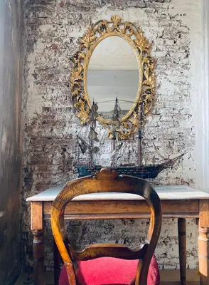 a mirror on a wall next to a table with a chair at The Lofty Mystic's Lodge in Antwerp
