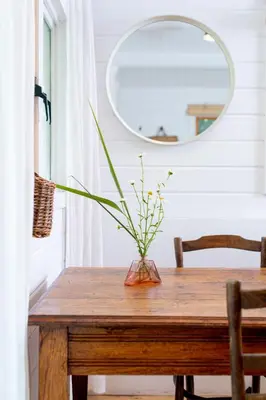 a vase on a wooden table with a mirror at Huisje aan de Vijver in Hamme