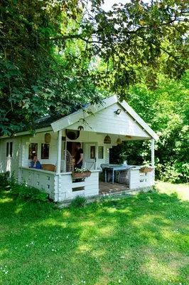 a small white house with a porch in a yard at Huisje aan de Vijver in Hamme