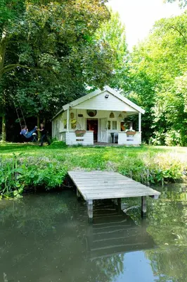 a house with a dock in the middle of a pond at Huisje aan de Vijver in Hamme