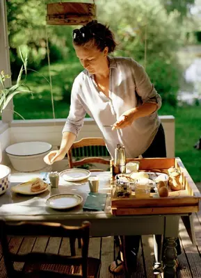 a woman standing at a table preparing food at Huisje aan de Vijver in Hamme
