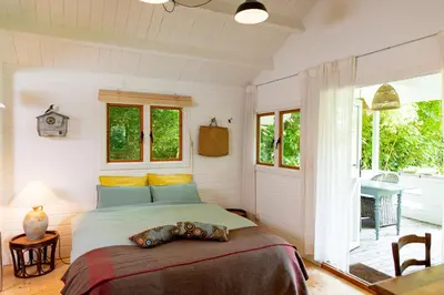a bedroom with a bed and a table and windows at Huisje aan de Vijver in Hamme