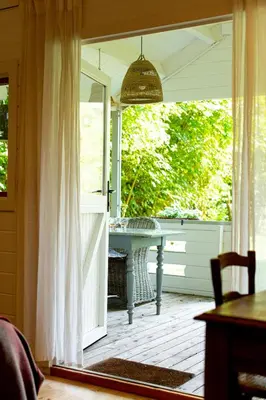 an open door to a patio with a table on a porch at Huisje aan de Vijver in Hamme