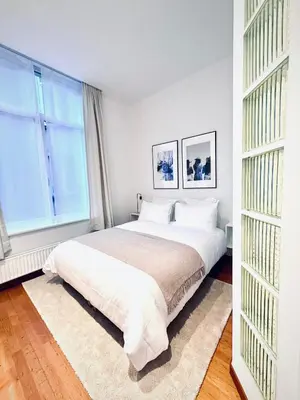 a white bedroom with a large bed and a window at Superbe appartement au coeur du Sablon in Brussels