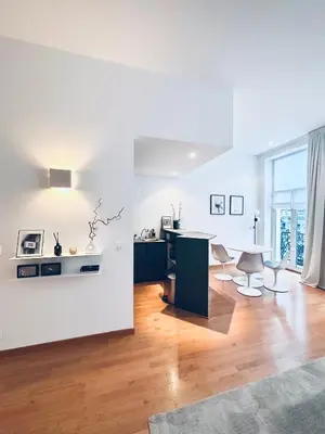 a white living room with a table and chairs at Superbe appartement au coeur du Sablon in Brussels
