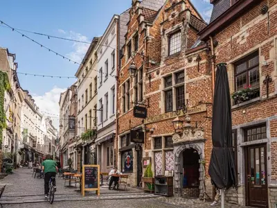a man riding a bike down a street with buildings at Superbe appartement au coeur du Sablon in Brussels