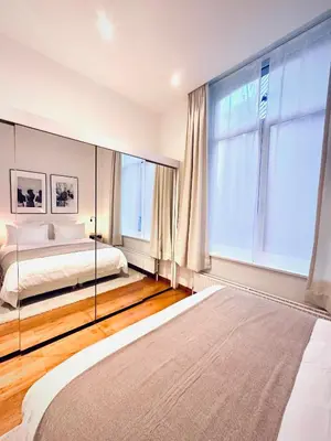 a bedroom with a bed and a large window at Superbe appartement au coeur du Sablon in Brussels