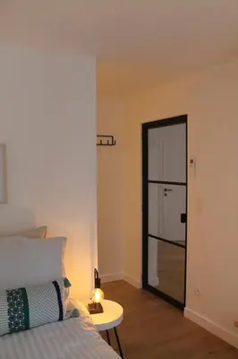 a bedroom with a bed and a door with a table at Cozy Central Apartment with Cathedral View on the 3rd floor in Antwerp