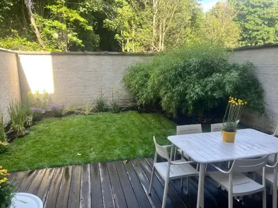 a wooden deck with a table and chairs in a garden at Completely renovated apartment in Antwerp