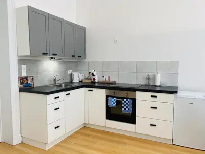 a kitchen with white cabinets and black counter tops at Studio calme et lumineux à Uccle in Brussels