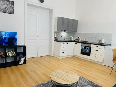 a kitchen with white cabinets and a wooden floor at Studio calme et lumineux à Uccle in Brussels