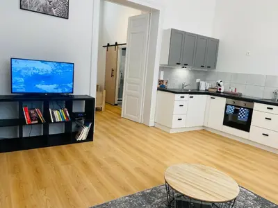 a kitchen with white cabinets and a wooden floor at Studio calme et lumineux à Uccle in Brussels