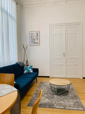 a living room with a blue couch and a table at Studio calme et lumineux à Uccle in Brussels
