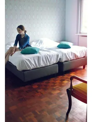 a young girl sitting on two beds in a room at Holiday home Zelenachten in Zele