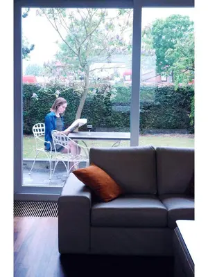 a woman sitting in a chair reading a paper at Holiday home Zelenachten in Zele