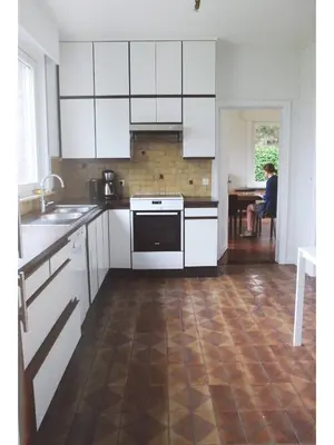 a kitchen with white cabinets and a wooden floor at Holiday home Zelenachten in Zele