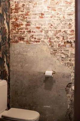 a bathroom with a white toilet and a brick wall at Chic 3BR Apartment near Antwerpen-Centraal Station in Antwerp