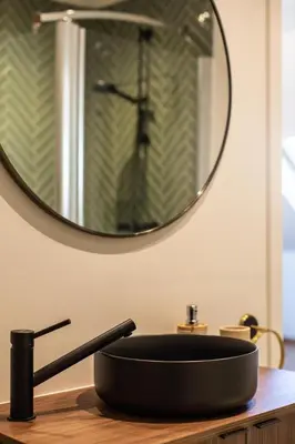 a black sink in front of a round mirror at Chic 3BR Apartment near Antwerpen-Centraal Station in Antwerp