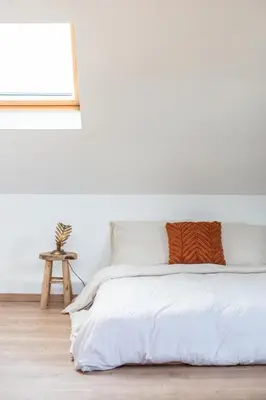 a bedroom with white walls and a bed with orange pillows at Chic 3BR Apartment near Antwerpen-Centraal Station in Antwerp