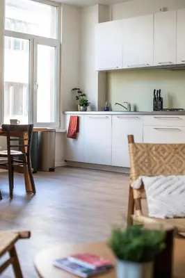 a kitchen with white cabinets and a table in a room at Chic 3BR Apartment near Antwerpen-Centraal Station in Antwerp