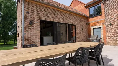 a wooden table and chairs on a patio at Gezellig vakantiehuis voor 12 personen in Boutersem