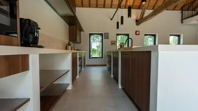 a kitchen with wooden cabinets and a long hallway at Gezellig vakantiehuis voor 12 personen in Boutersem