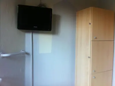 a flat screen tv on the wall next to a refrigerator at The82 Hostel Louise in Brussels