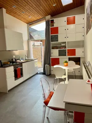 a kitchen with white cabinets and a table and chairs at Studio vintage banlieue BXL in Genval