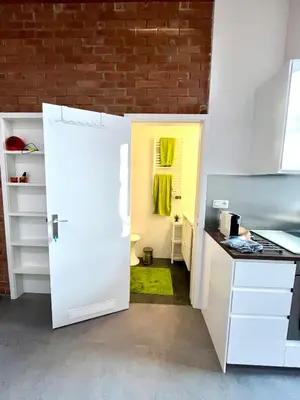 a kitchen with a white door and a brick wall at Studio vintage banlieue BXL in Genval