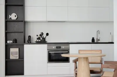 a kitchen with white cabinets and a table at Appartement t'Zuid with underground parking in Antwerp