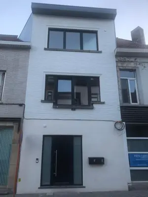 a white house with black windows on a street at Holiday Small Shared Room in Gent in Ghent