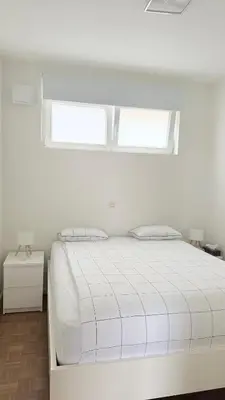 a white bed in a white room with two windows at Arm Apart in Brussels
