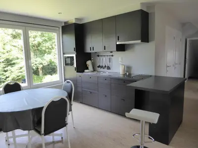 a kitchen with black cabinets and a table and chairs at Apartment in a villa in Kasterlee
