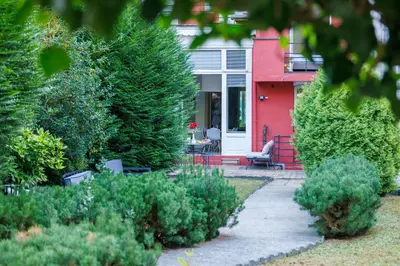 a red house with a porch with a chair and trees at Mas Europe by Sweett in Brussels