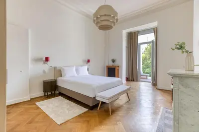 a white bedroom with a white bed and a window at Mas Europe by Sweett in Brussels