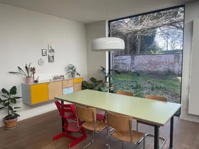 a dining room with a table and chairs and a window at Spacious house with big garden close to the city in Ghent