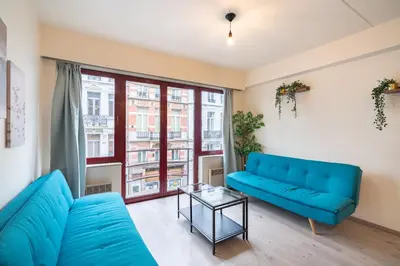 a living room with a blue couch and a glass table at Bright and Central Antwerp Apartments in Antwerp