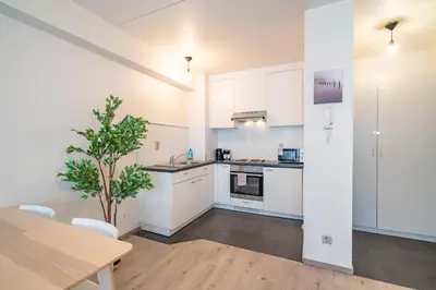 a kitchen with white cabinets and a wooden table at Bright and Central Antwerp Apartments in Antwerp