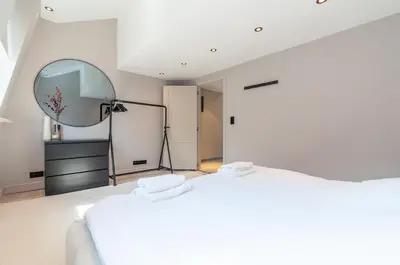 a white bedroom with a large white bed and a mirror at Holiday Home in Antwerp in Antwerp