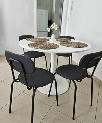 a table with four chairs and a white table with a vase at Proche du Centre de Bruxelles appartement 5 personnes in Brussels