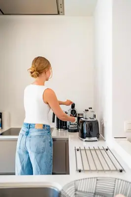 a woman standing in a kitchen with a coffee maker at La Petite Foret Design Flat in Antwerp City in Antwerp
